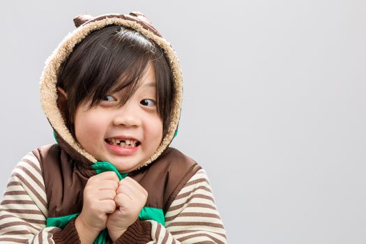 Cute Asian girl shivering in coat, studio isolated white background.