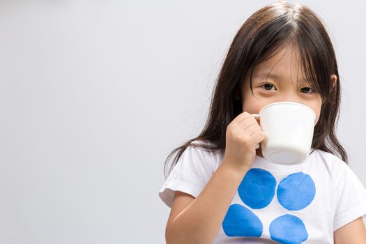 Kid drinking milk on studio isolated white background.