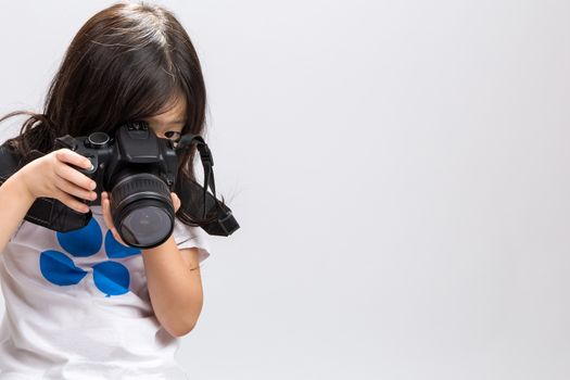 Little kid using DSLR camera to take some photos in studio.