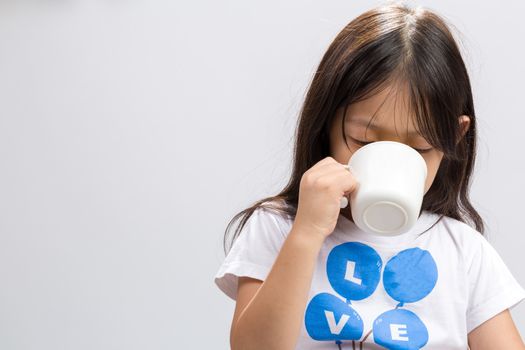 Kid drinking milk on studio isolated white background.