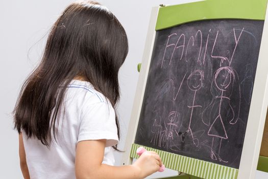 Little kid writing something on blackboard studio isolated.