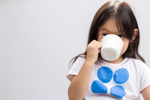 Kid drinking milk on studio isolated white background.