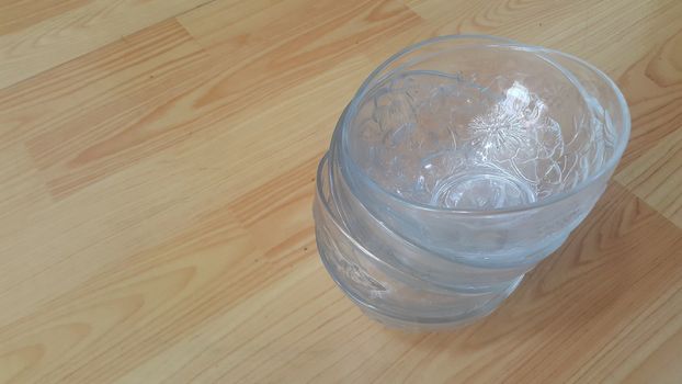 Top view of empty white glass bowls on a wooden floor. Glass bowl with flowers made on its wall