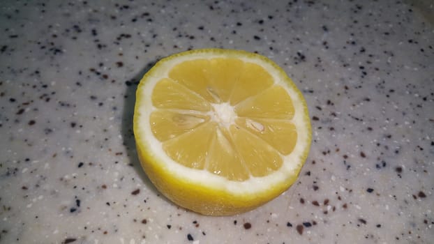 Fresh lemon slices with yellow peelings placed on a grey floor. Top view of fresh juicy lemon slice background