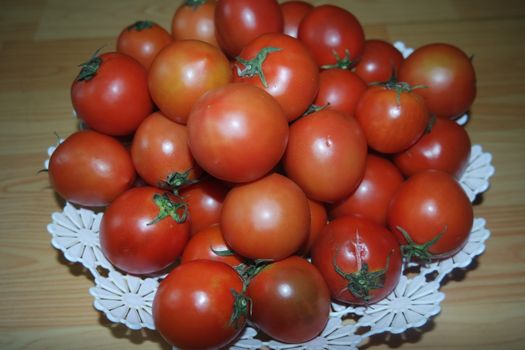 Close-up view of red tomatoes in white basket on a wooden floor in market for sale. A fruit background for text and advertisements