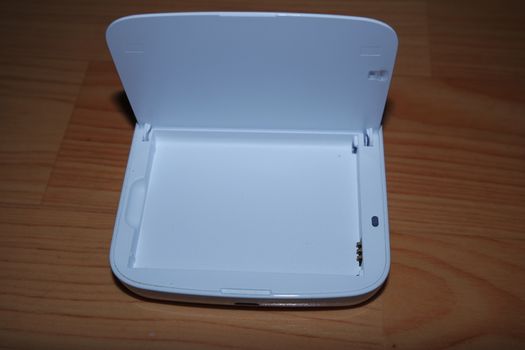 White colored battery charging box for electronic devices like mobile phone. Potable charging box is placed on a wooden floor.