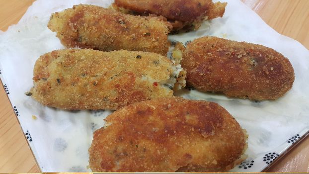 Closeup perspective view of home made spicy and delicious croquettes served in ceramic plate over wooden floor