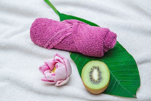 Rolled purple towel and flower with leaf