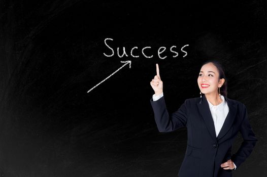 Happy young business woman pointing to success text with blackboard background
