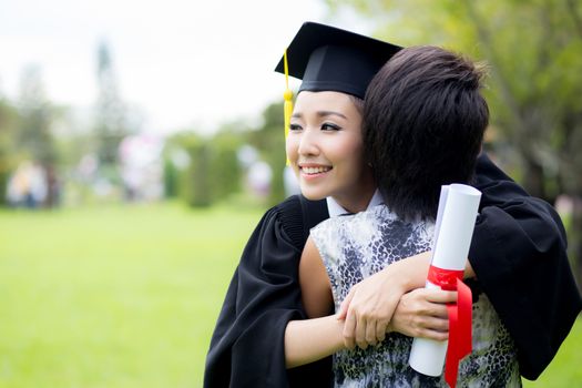 young female graduate hugging her friend at graduation ceremony