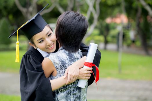 young female graduate hugging her friend at graduation ceremony