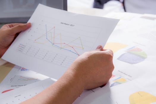 Financial paper charts with hold hand, graphs and notebook on the table