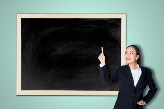 Happy young business woman pointing to empty chalkboard
