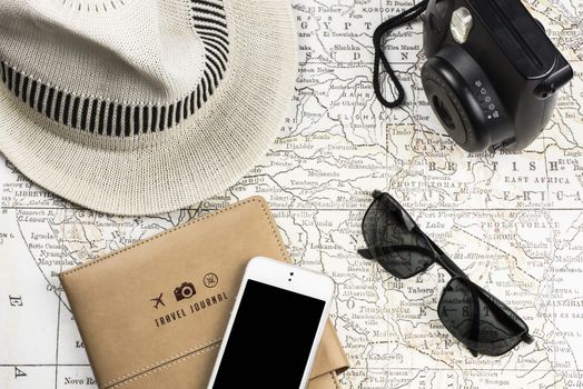 Photography of an ancient Map with a instant Camera like Polaroid, mobile phone (with black screen) sunglasses and white hat