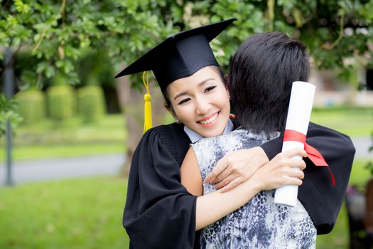 young female graduate hugging her friend at graduation ceremony