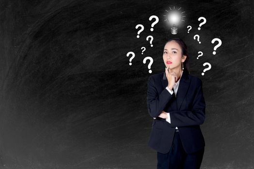 woman is standing with a light bulb and question marks blackboard background