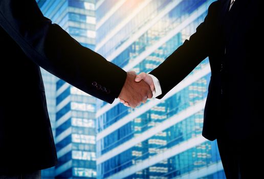 Hand shake between a businessman and a businesswoman with building background