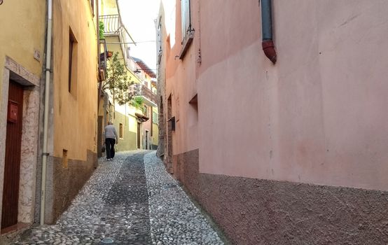 Concept: old age. An elderly man trudges along a cobblestone street in an ancient Italian village