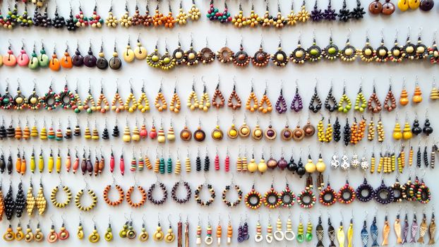 Concept: the value of craftsmanship. Many handmade colored wooden earrings displayed in a row for sale