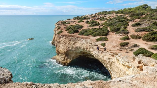 Panoramic view of the ocean cliffs of the Algarve, Portugal, with cloudy blue sky