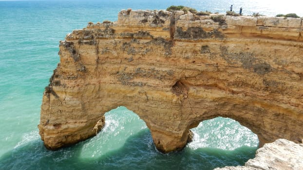 Panoramic view of the ocean cliffs of the Algarve, Portugal, with orange rocks on the blue sea