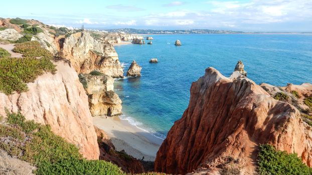 Panoramic view of the ocean cliffs of the Algarve, Portugal, with cloudy blue sky