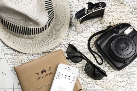 Photography of an ancient Map with a instant Camera like Polaroid, mobile phone (electronic boarding pass) sunglasses, flask in stainless steel and white hat