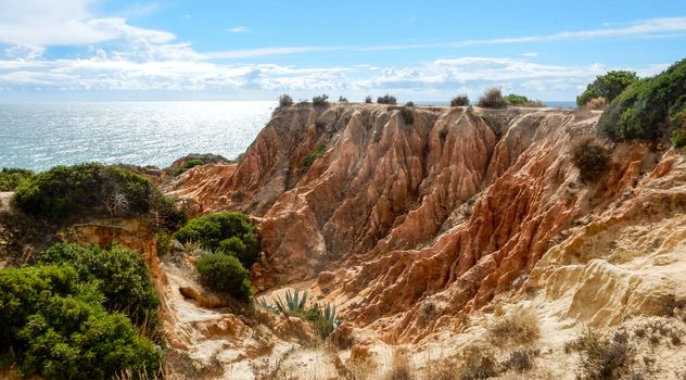 Panoramic view of the ocean cliffs of the Algarve, Portugal, with cloudy blue sky