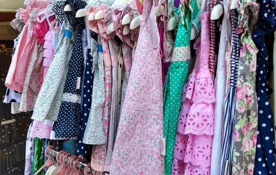 Fashion also for children: lots of baby clothes hung and pressed against each other on a stand for sale