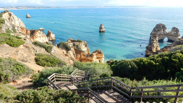 Panoramic view of the ocean cliffs of the Algarve, Portugal, with orange rocks on the blue sea