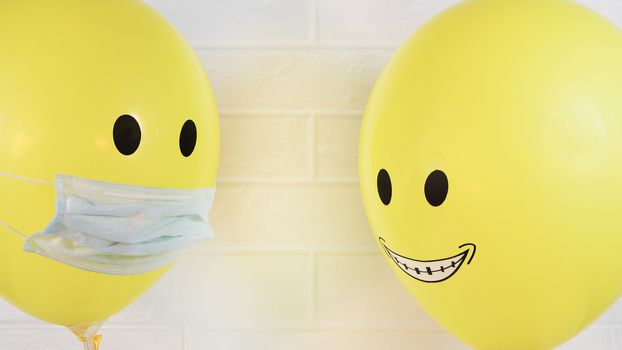 Two smiling yellow balls, one in a medical mask is quarantined for an epidemic of a virus, flu, Allergy or covid 19.