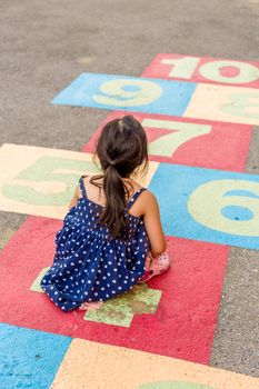 Young girl playing hopscotch on playground with happiness.