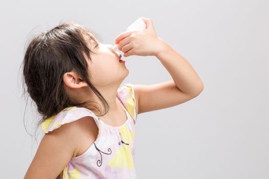 Sick Asian girl spray nasal medicine in nose.