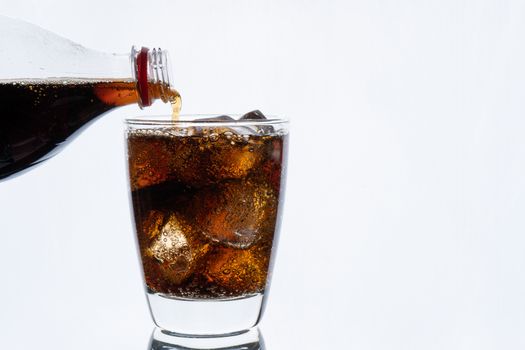 Cold drinking, pouring soda from bottle, glass of cola with ice for hot and summer drink isolated on white background