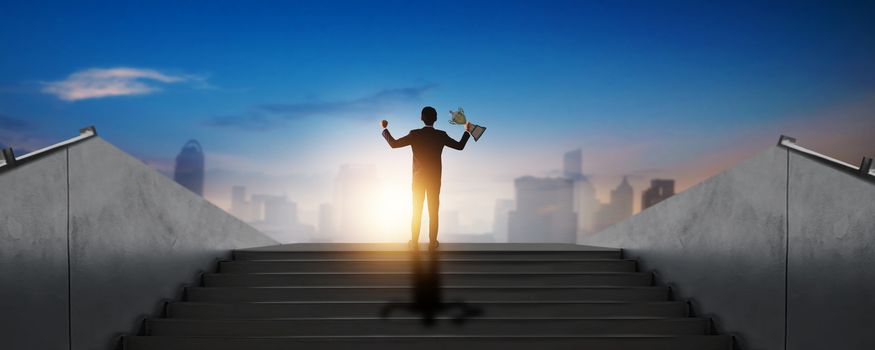 success businessman winner holding award, champion, victory and prize on stair with city background 