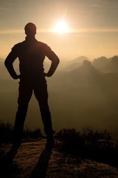 Self confident hiker on the peak of sandstone rock in rock empires park and watching over the misty and foggy morning