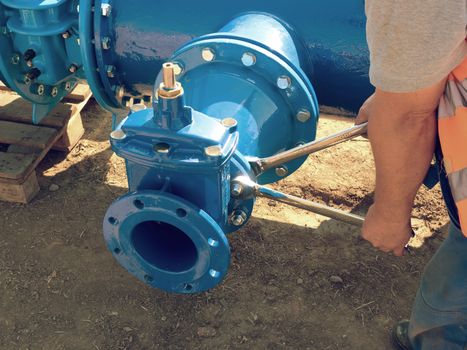 Worker hands screwing Gate valve with nuts on new dring water piping.  Water suply construction with new Gate valves and reduction member. Pipe fittings joint with new screws and nuts. 