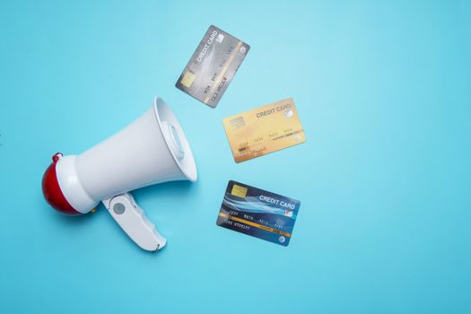 Megaphone with credit card on blue background, Cheap interest public relations concept