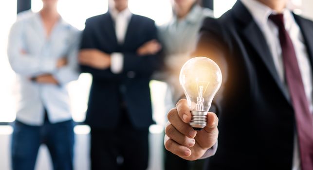 Businessman holding light bulb with team of business people background brainstorming and idea concept