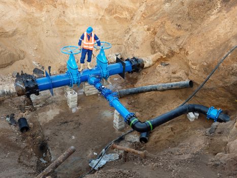 Technical expert underground at  gate valve on 500mm drink water pipes joined with new black waga multi joint members into old pipeline system. Check of repaired piping before covering by clay. Asphalt isolation 