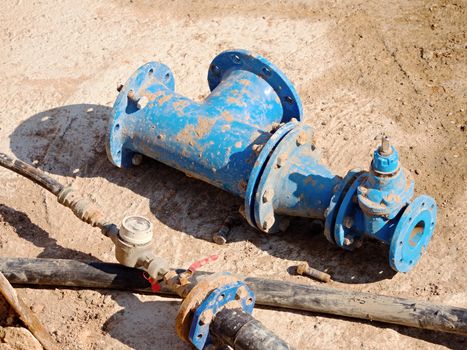 Old drink water pipes, used blue gate valve and reduction joint members. Water supply interrupted, repairing of infrastructure. Metal  corrosion texture. PVC pipeline. 