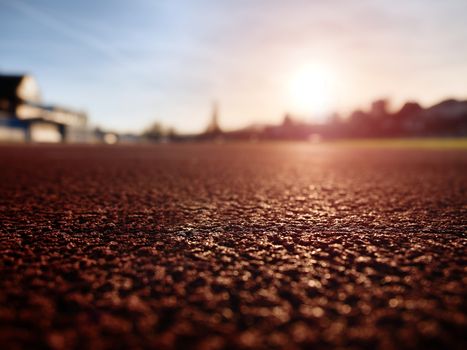 Detailed  Running Track At A Sport Stadium. Close up red racetrack ground on outdoor stadium. Sun rays.  Sport and healthy lifestyle concept, training workout