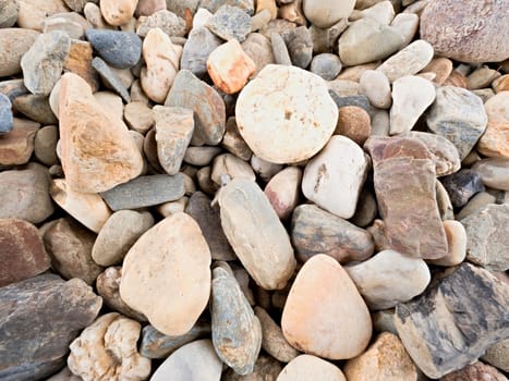 Old stony pavement from natural gravel, dry rounded stones, Traditional building materials, small colorful pebbles.