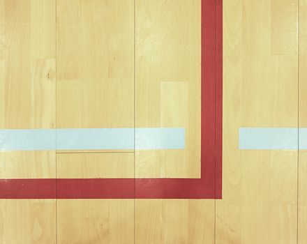 Red corner and blue line. Worn out wooden floor of sports hall with colorful marking lines