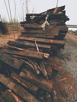 Extracted old wooden ties in stock. Old oiled used oak railway sleepers stored after big reconstruction of old railway station. 