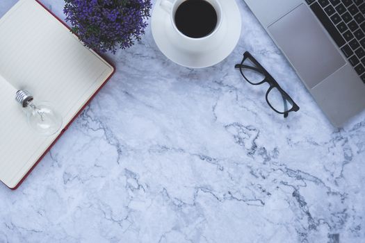 Flat lay creative and designer background with light bulb and office tools on white marble background