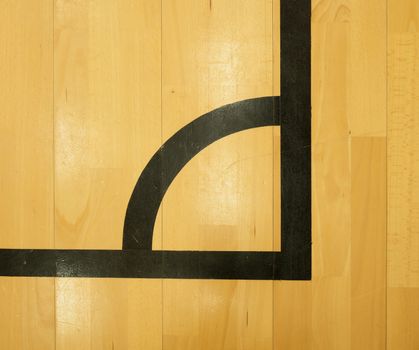 Black corner. Worn out wooden floor of sports hall with colorful marking lines