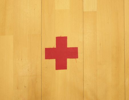 Red cross, playground corner. Worn out wooden floor of sports hall with colorful marking lines