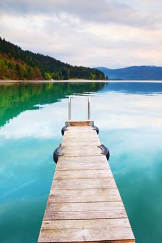 Empty wooden mole on  blue Alps lake, wharf for hired boats in marina. Ready for trip ships.