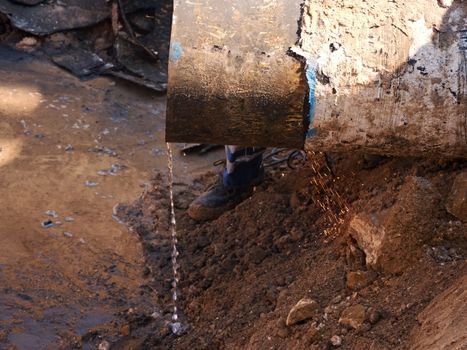 Rusty Old Iron Pipe With Clear Water Flowing From It. Waste water drain pipe in clay